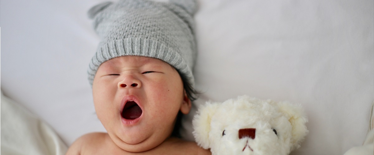 Bébé avec son bonnet naissance et son doudou